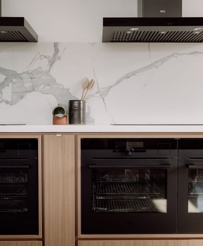 Black AEG Ovens in a white marble kitchen