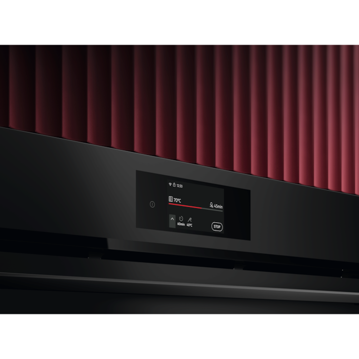 Close-up of an AEG oven control panel with the colour touchscreen lit, set into a dark kitchen